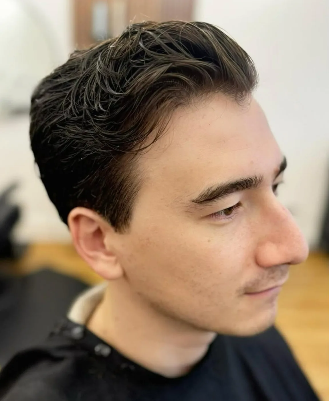 Finished men's haircut — classic side-part on a younger client
