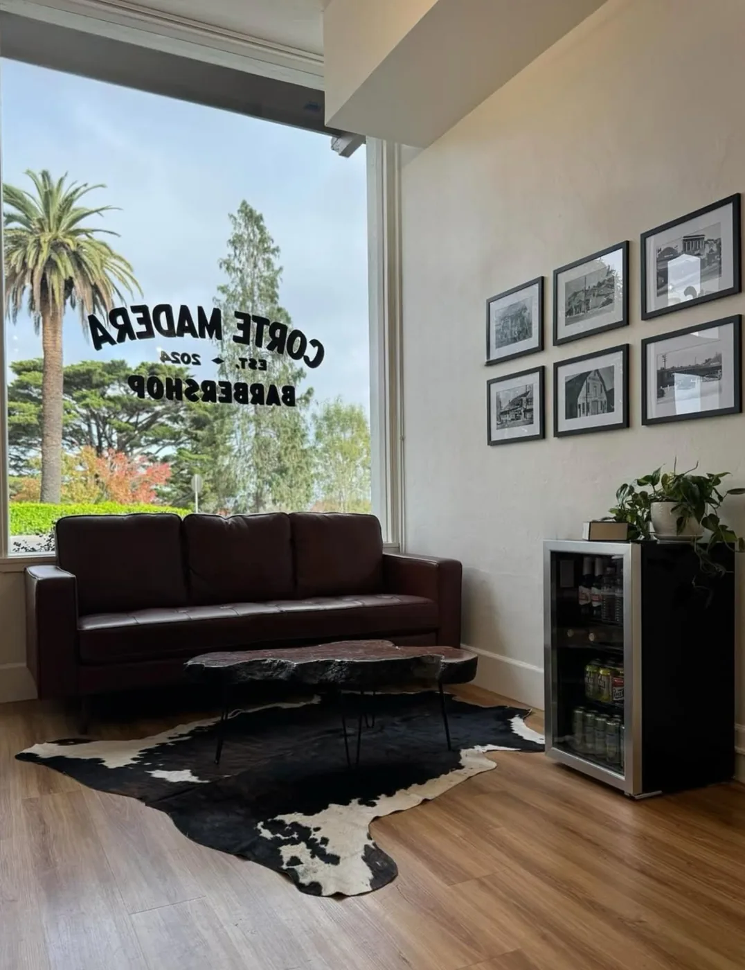 The waiting area — leather couch under the gold-leaf window with a wall of black-and-white Corte Madera history photos