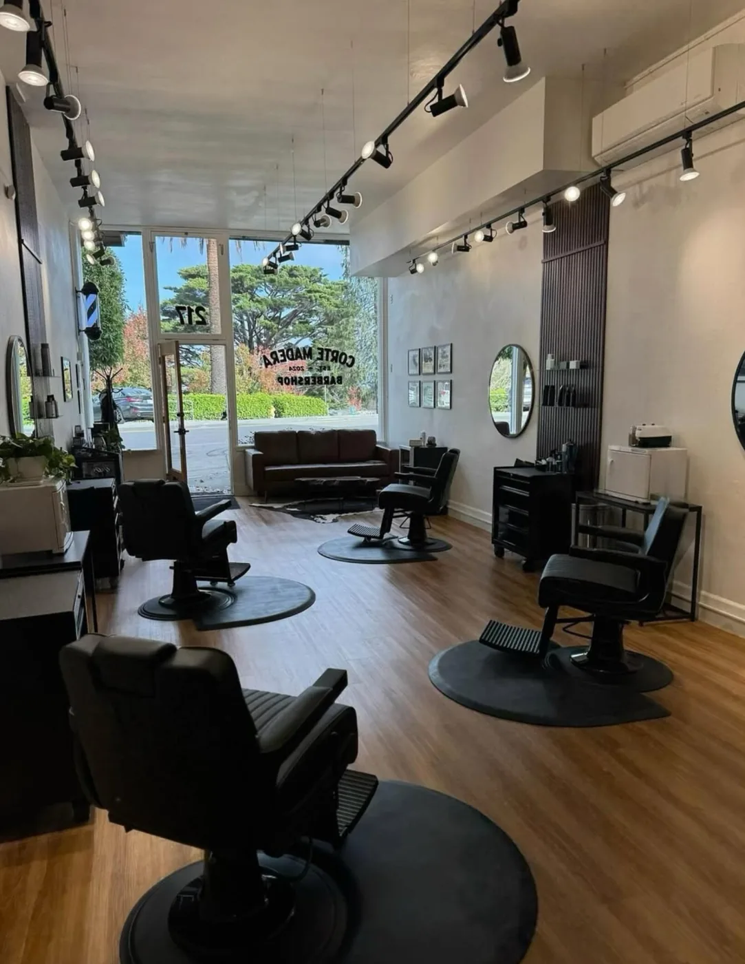 The shop floor — three black barber chairs, leather couch and the gold-leaf storefront window